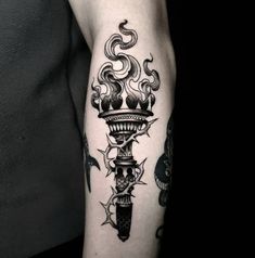 a man's arm with a black and white tattoo design on the left forearm