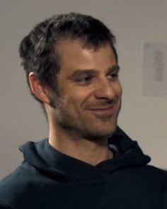 a man in a black hoodie is smiling