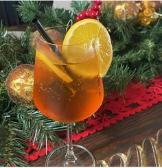 a close up of a drink in a wine glass on a table with christmas decorations