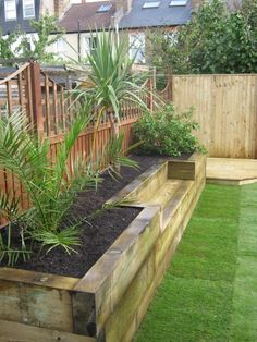 a wooden planter filled with lots of plants next to a fenced in area