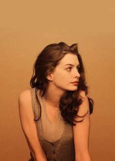 a woman sitting on top of a wooden floor next to a brown and white wall