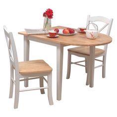 a table with two chairs and a bowl of fruit on the table next to it