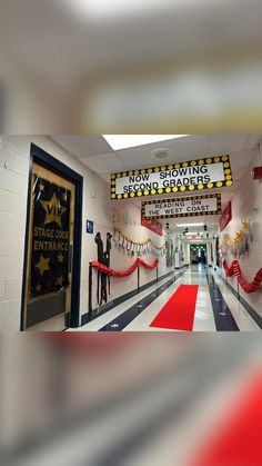 an empty school hallway with red carpet and yellow stars hanging from the ceiling above it