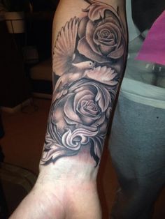 a black and white rose tattoo on the left arm, with a bird flying over it