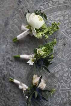 three white flowers are arranged on a gray surface