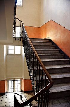 an empty staircase with wrought iron railings and tiled flooring in front of a window