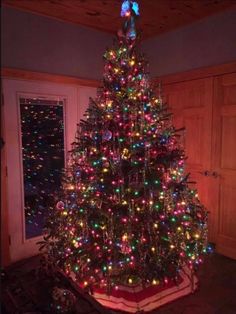 a brightly lit christmas tree in the corner of a room