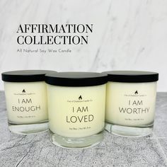 three candles sitting next to each other in front of a marble background with the words affirmation collection all natural soy wax candle