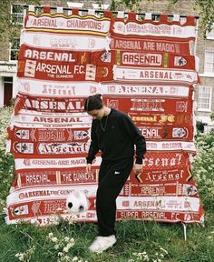 a man standing next to a giant red and white banner with soccer logos on it