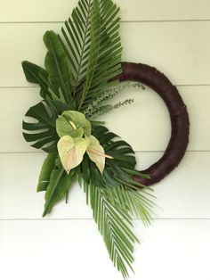 a wreath with leaves and flowers hanging on the wall