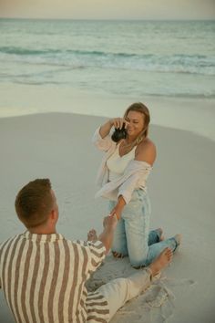 a man taking a photo of a woman on the beach