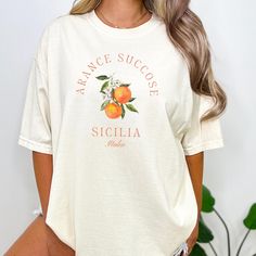 Featuring a retro orange fruit design, the Aranci Di Sicila T Shirt is perfect for any occasion. The shirt's unique design evokes a vintage Italian aesthetic that is comfortable and stylish. Whether you're a foodie or you're simply a lover of all things Italy, this cozy tee is a must-have addition to your wardrobe. Give it as a gift to someone special your life or treat yourself to this unique and timeless piece. * PRODUCT DETAILS * ♥ Double needle stitching on all seams. The garment is sewn aro Vintage Summer Top With Fruit Print, Vintage Fruit Print Top For Summer, Vintage Fruit Print Crew Neck Tops, Vintage Crew Neck Tops With Fruit Print, Vintage Cotton Tops With Fruit Print, Trendy Apricot Short Sleeve Top, Trendy Short Sleeve Apricot Top, Orange Printed Short Sleeve Tops, Casual Orange Fruit Print Top