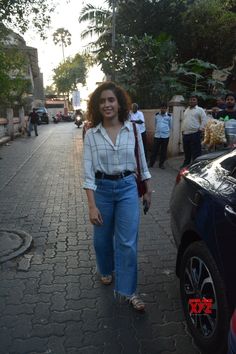 a woman is walking down the street with her hand in her pockets