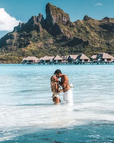 two people standing in the ocean kissing each other