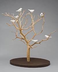 a group of white birds sitting on top of a tree in front of a gray background