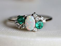 14k gold opal ring, opal emerald ring, emerald diamond ring, opal diamond ring, opal cluster ring, emerald cluster ring, opal gold ring Available in 9k/14k yellow, rose or white gold. Same design can be made also with other custom gemstones per request. Product details:- Solid gold- Diamond - 1.5mm, 2mm, - Australian Opal - 4x6mm- Emerald - 3mm  - 1.1mm band- Diamond clarity - VS, Color - E-F- Made to order - 8 to 10 business days.Ring size - US 3 to US 9 (for smaller or larger ring size, please Multi Gem Engagement Ring, Emerald And Opal Engagement Ring, Emerald Cluster Ring, Hippie Engagement Ring, Cluster Ring Engagement, Engagement Ring Opal, 14k Gold Opal Ring, Smaragd Ring, Raw Diamond Rings