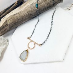 Your favorite gemstone is just on the horizon! This beautiful slab of rainbow moonstone drops from a unique, hand forged pendant which blends textures and shapes. This beauty is accented with textured, oxidized sterling chains and tiny heishi turquoise gemstones. •14k gold filled and sterling silver •Moonstone and turquoise •Pendant Dimensions: 1.25 x 1.5" •Length: 17" Forged Pendant, Sterling Chains, On The Horizon, Jewelry Repair, Turquoise Pendant, The Horizon, Turquoise Gemstone, Bar Necklace, Hand Forged