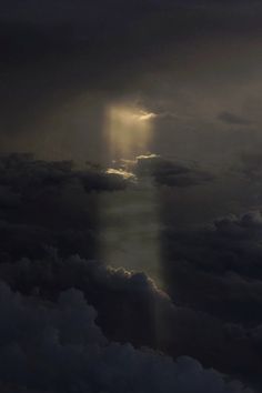 the sky is filled with dark clouds and light shining from behind an object in the distance