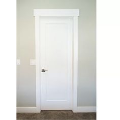 an empty room with a white door and carpeted floor in front of the wall