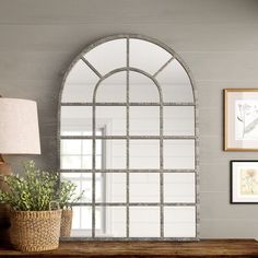 a mirror sitting on top of a wooden table next to a lamp and potted plant