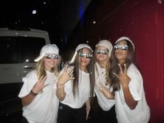 four people wearing white shirts and sunglasses posing for the camera with their hands in the air