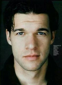 a close up of a person wearing a black shirt and looking at the camera with a serious look on his face