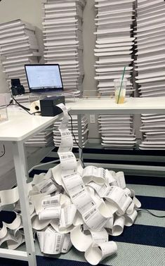 a pile of papers sitting on the floor in front of a desk with a computer