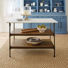 a kitchen with blue cabinets and white marble counter tops, including a serving tray on a coffee table