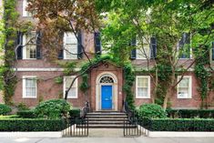 a blue door sits in front of a brick building with ivy growing all over it