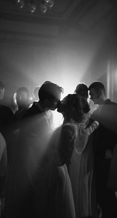 black and white photograph of people dancing in a dance hall with light coming through the ceiling