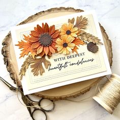 a card with some flowers on it next to scissors and thread in front of a piece of wood