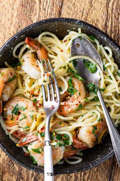 pasta with shrimp and parsley in a skillet on top of a wooden table