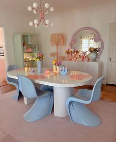 a dining room table with blue chairs and a mirror on the wall in front of it