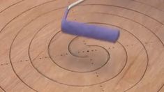 a blue object is in the middle of a circular pattern on a wooden surface with circles around it