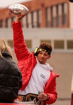 a man holding up a football in the air while standing next to a woman with her arm raised