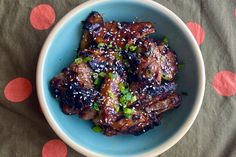 a blue bowl filled with meat covered in sesame seeds and green onion sprinkles