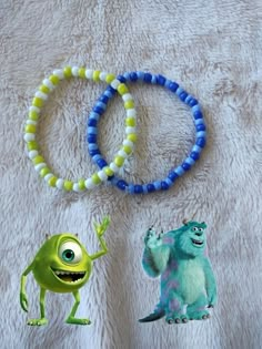 two bracelets with monsters on them sitting on a bed next to each other,