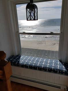 a window seat with a blue and white blanket on it looking out at the ocean