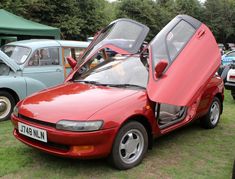 a red car with its doors open on the grass