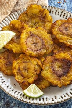 some fried food on a white plate with lime wedges