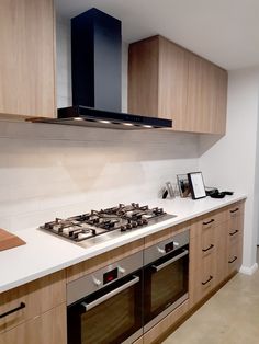 a stove top oven sitting inside of a kitchen next to wooden cabinets and counter tops