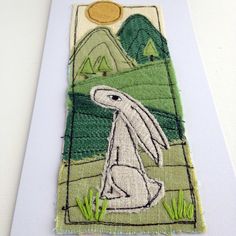 a white rabbit is sitting in the grass with mountains and trees on it's back