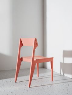 an orange chair sitting in front of a white wall