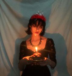 a woman holding a plate with a lit candle in her hand and wearing a red headband