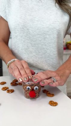 a woman holding a cup with pretzels on it and making a reindeer face