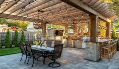 an outdoor kitchen and dining area in a backyard