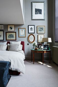 a bed room with a neatly made bed and pictures on the wall