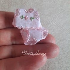 a hand holding a tiny pink baby bib