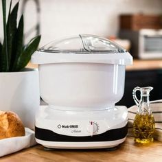 a white food processor sitting on top of a wooden table next to a loaf of bread