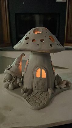 a mushroom shaped house is lit up by the light of a candle in front of a fireplace